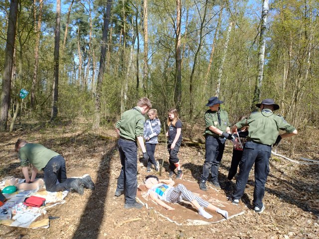 Harcerze ćwiczą scenariusz ratunkowy podczas gry terenowej w lesie